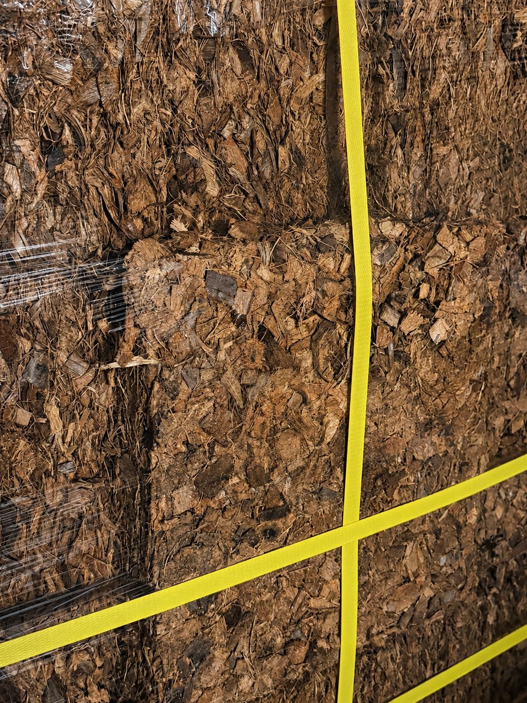 Close view of compressed coconut material secured with yellow straps