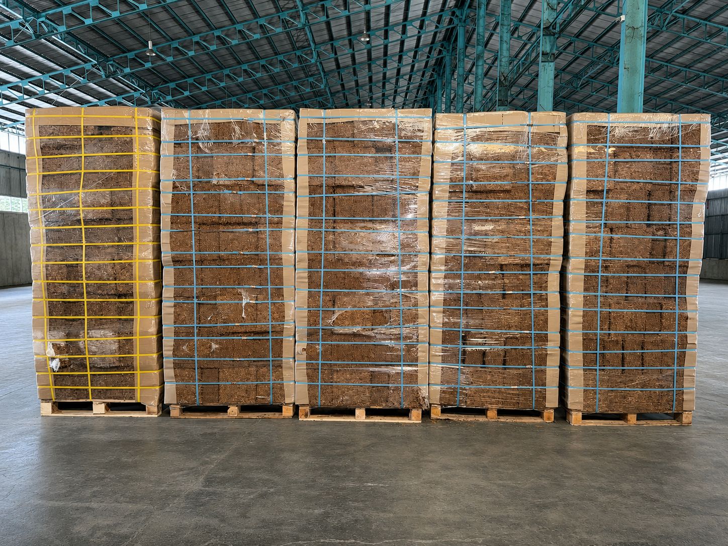 Palletized compressed coconut products secured with straps in a warehouse